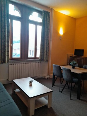 A room with a wooden table, two chairs, a sofa, a TV, and a window with curtains. - 2nd floor, swimming pool, hammam, parking, tv, 35m², Pra Loup (Jausiers)