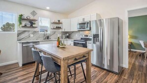 A modern kitchen with a central island, stainless steel appliances, and a wooden floor.