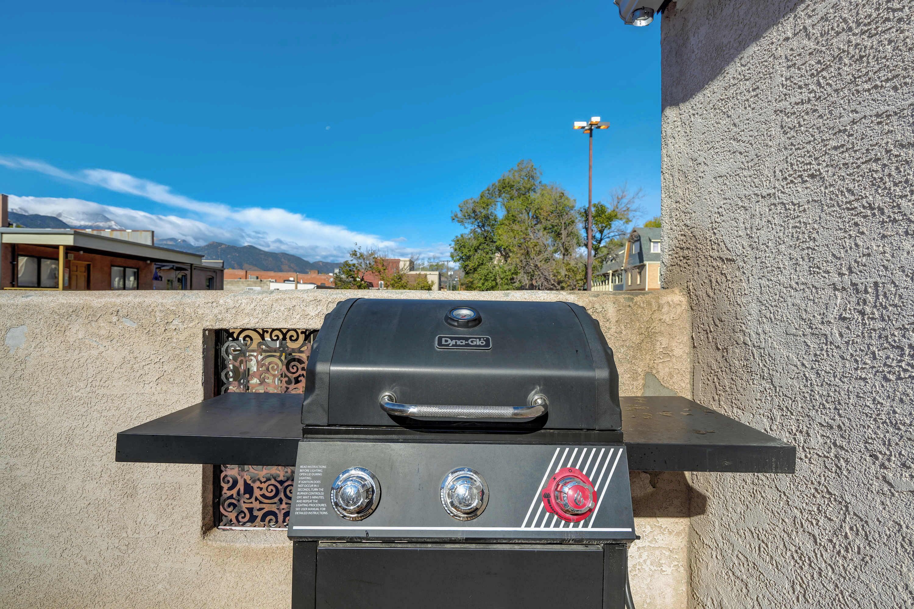 Una parrilla de gas con un panel de control, frente a una pared con textura.