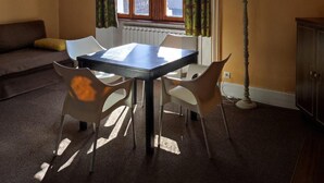 En matplats med ett bord och stolar, ett fönster med gardiner, en lampa och en soffa.
