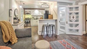 A modern kitchen with white cabinets, stainless steel appliances, and a central island with stools. - Miners Escape! Timeless District Cozy Haven (Colorado Springs)
