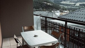 Ein Balkon mit Tisch und Stühlen, der einen Blick auf eine Berglandschaft bietet.
