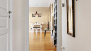 A hallway with a dining area in the background, featuring a table and chairs.