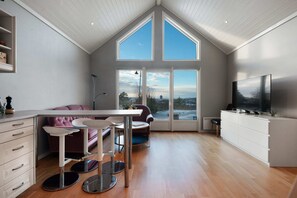 A modern kitchen with a dining area, large windows, and a TV. - Sea-View Anexet in Fjällbacka by AJF Dream Living (Fjällbacka)