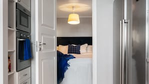 A compact kitchen with a built-in oven and microwave, a refrigerator, and a wooden floor. - Sea-View Anexet in Fjällbacka by AJF Dream Living (Fjällbacka)