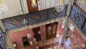 Un vestíbulo amplio con techo alto, múltiples lámparas colgantes y una zona de estar central con una mesa de centro y sillas.