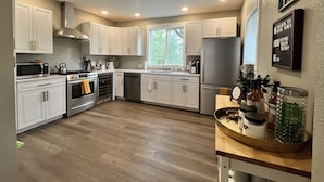 Una cocina moderna con armarios blancos, electrodomésticos de acero inoxidable y encimera de madera.