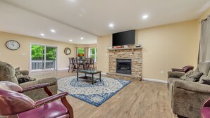 A spacious living room with a fireplace, a dining area, and a large window. - Holiday Home Near Lake and Pool (Tobyhanna)