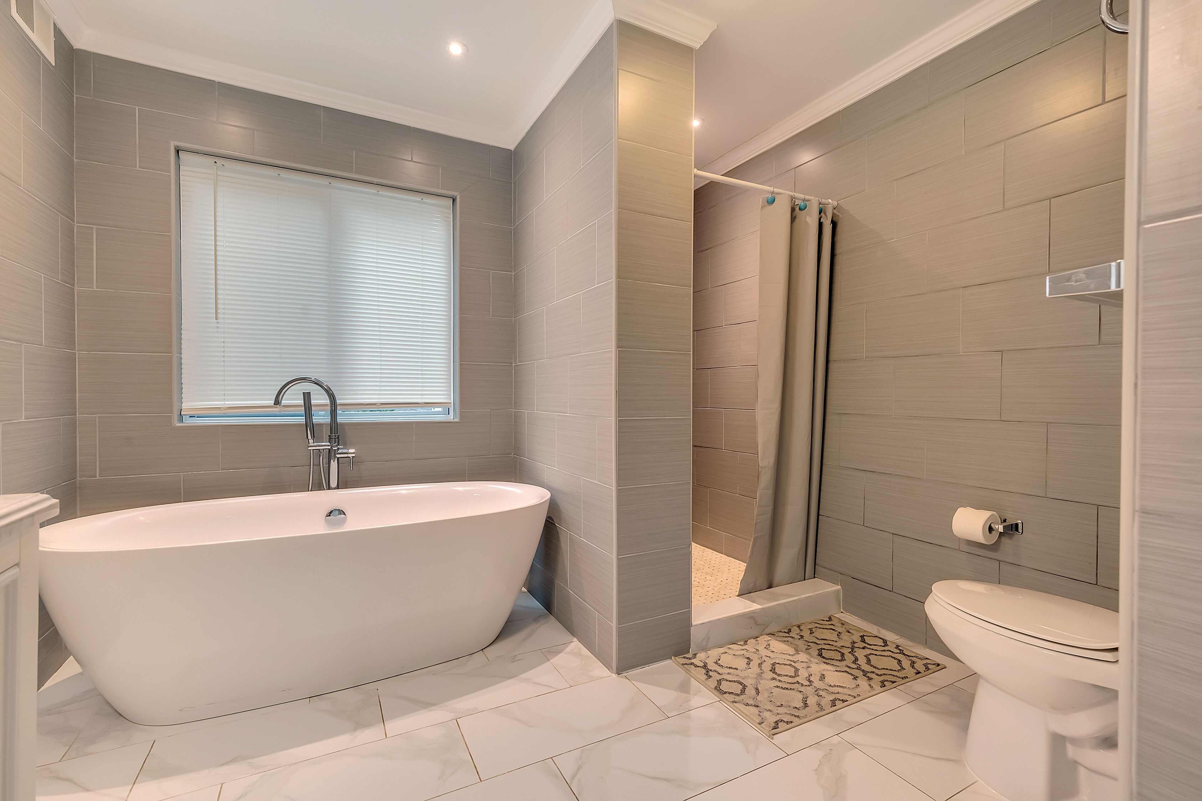A modern bathroom with a freestanding bathtub, a shower enclosure, and a toilet.