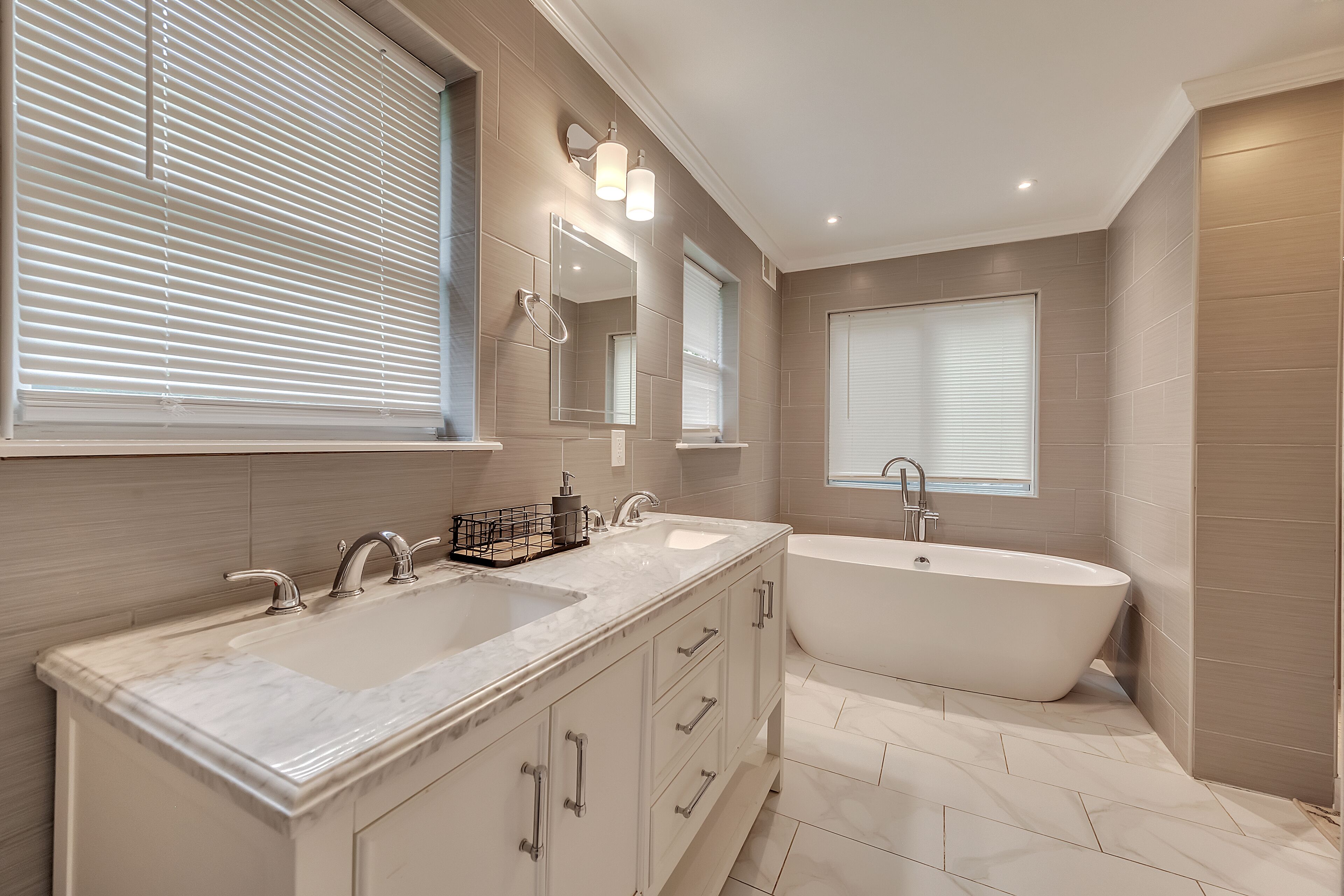 A modern bathroom with two sinks, a bathtub, and a large mirror.