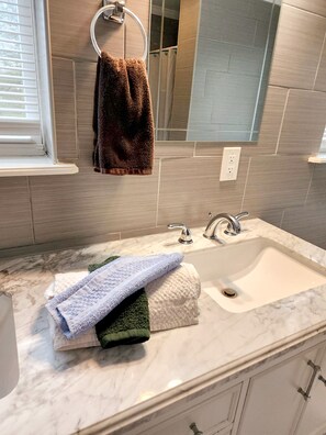 A bathroom with a marble sink, two faucets, and a towel rack with a brown towel. - Holiday Home Near Lake and Pool (Tobyhanna)