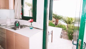 Una cocina con un lavamanos, una ventana con cortinas y vistas a un jardín.