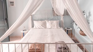 Una cama con dosel, una mesita de noche, un taburete pequeño y un aire acondicionado instalado en la pared.