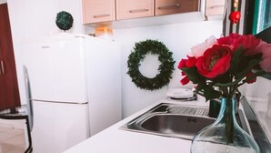 Una cocina con armarios blancos, un lavamanos de acero inoxidable y un florero con flores sobre la encimera.