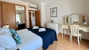 Ett hotellrum med en säng, ett skrivbord, en stol, en byrå och en tavla på väggen.