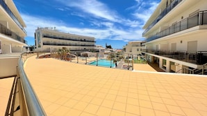 Ett poolområde på taket med en klarblå himmel, en pool och byggnader i bakgrunden.