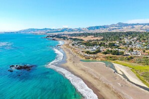 Un pueblo costero con playa, casas y montañas al fondo.