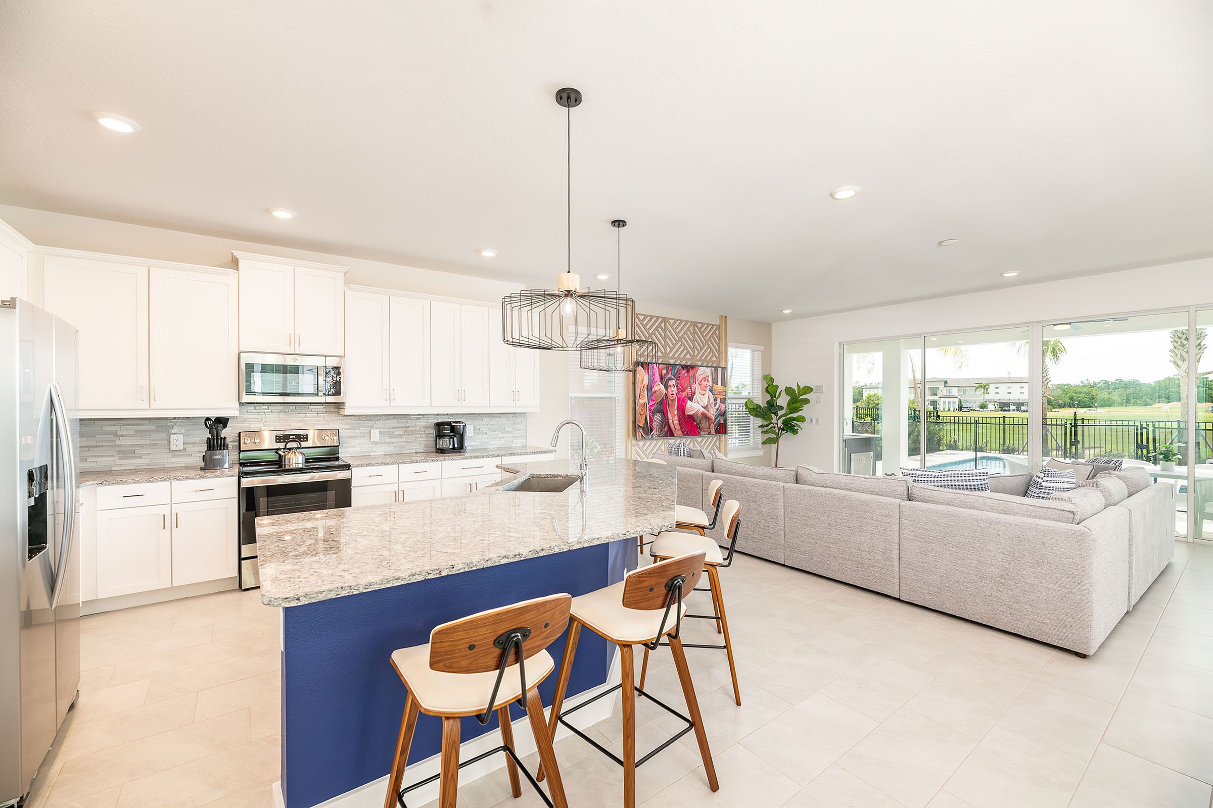 A modern kitchen with a large island, bar stools, and a view of the outdoors.