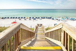 A wooden staircase leading to a beach with umbrellas and lounge chairs.