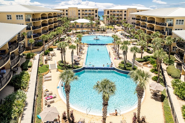 A resort with multiple swimming pools, palm trees, and a beachfront view.