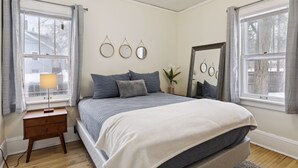 Une chambre à coucher avec un lit, une table de chevet, une lampe et des fenêtres.