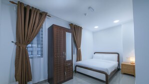 A bedroom with a bed, a wardrobe, a nightstand, and a window with curtains.