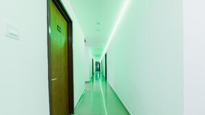 A hallway with a door labeled '30B' and a green-lit ceiling.