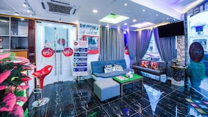 A hotel lobby with a sofa, a red chair, a coffee table, and a TV screen.