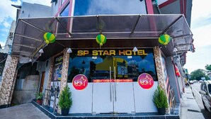 The SP Star Hotel entrance with a clear sign, two potted plants, and a welcome mat.