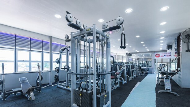 A gym with various exercise machines, a bench, and a blue mat on the floor.