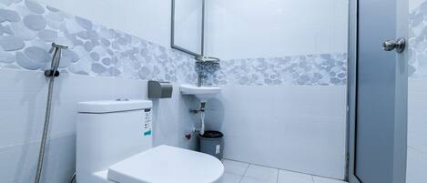 Un baño moderno con inodoro, lavamanos y ducha.