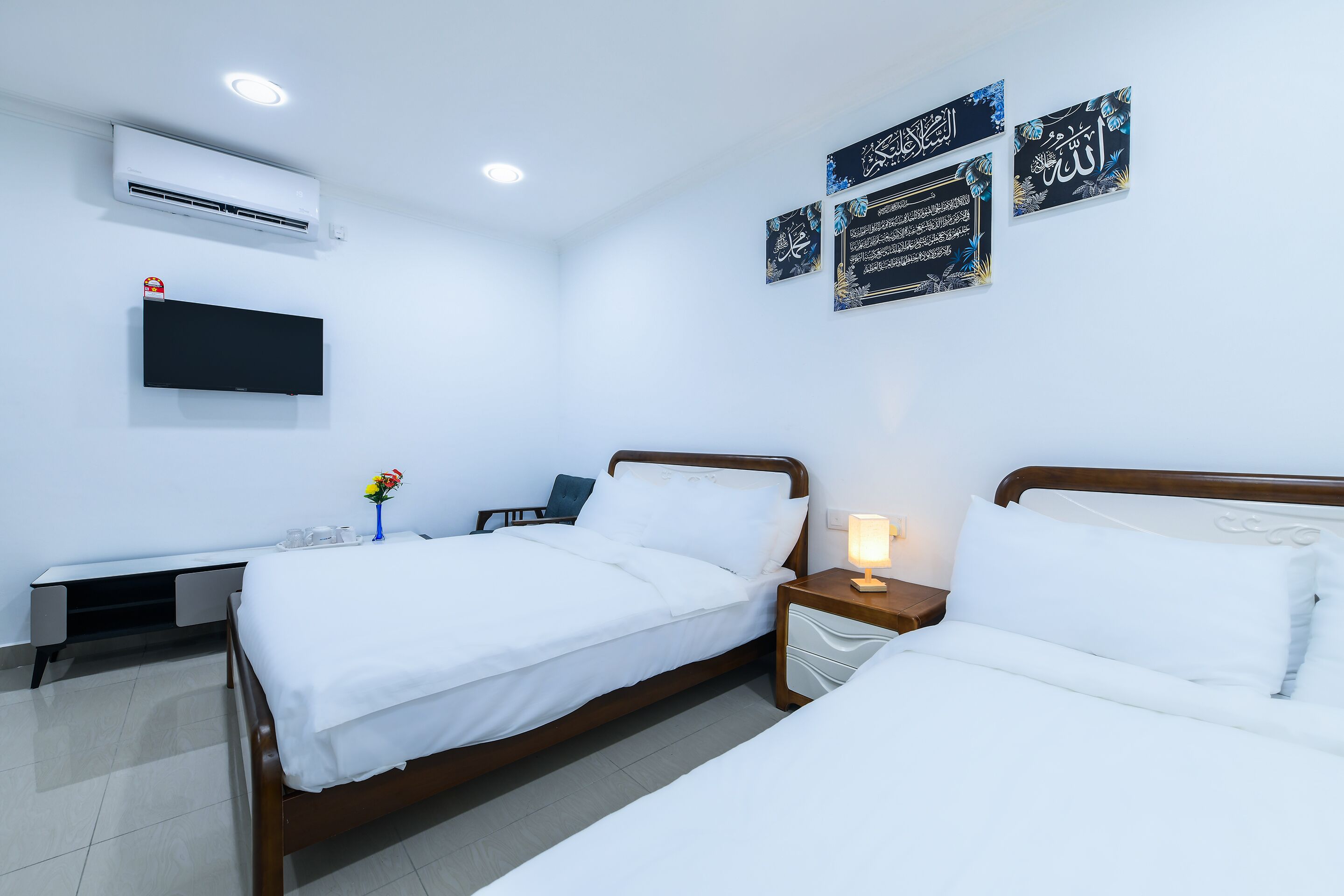 Habitación de hotel con dos camas, un televisor de pantalla plana, un equipo de aire acondicionado y decoración en las paredes.