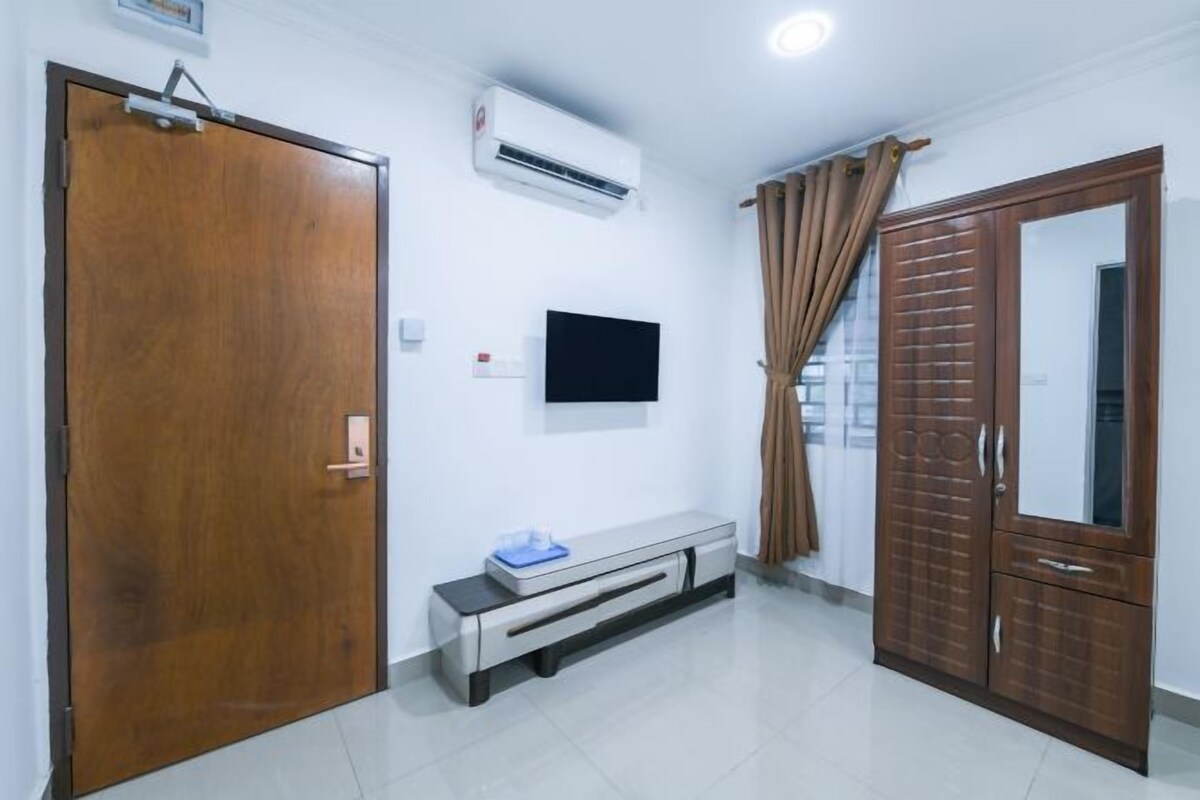Una habitación con puerta de madera, un banco, televisor montado, aire acondicionado y un armario.