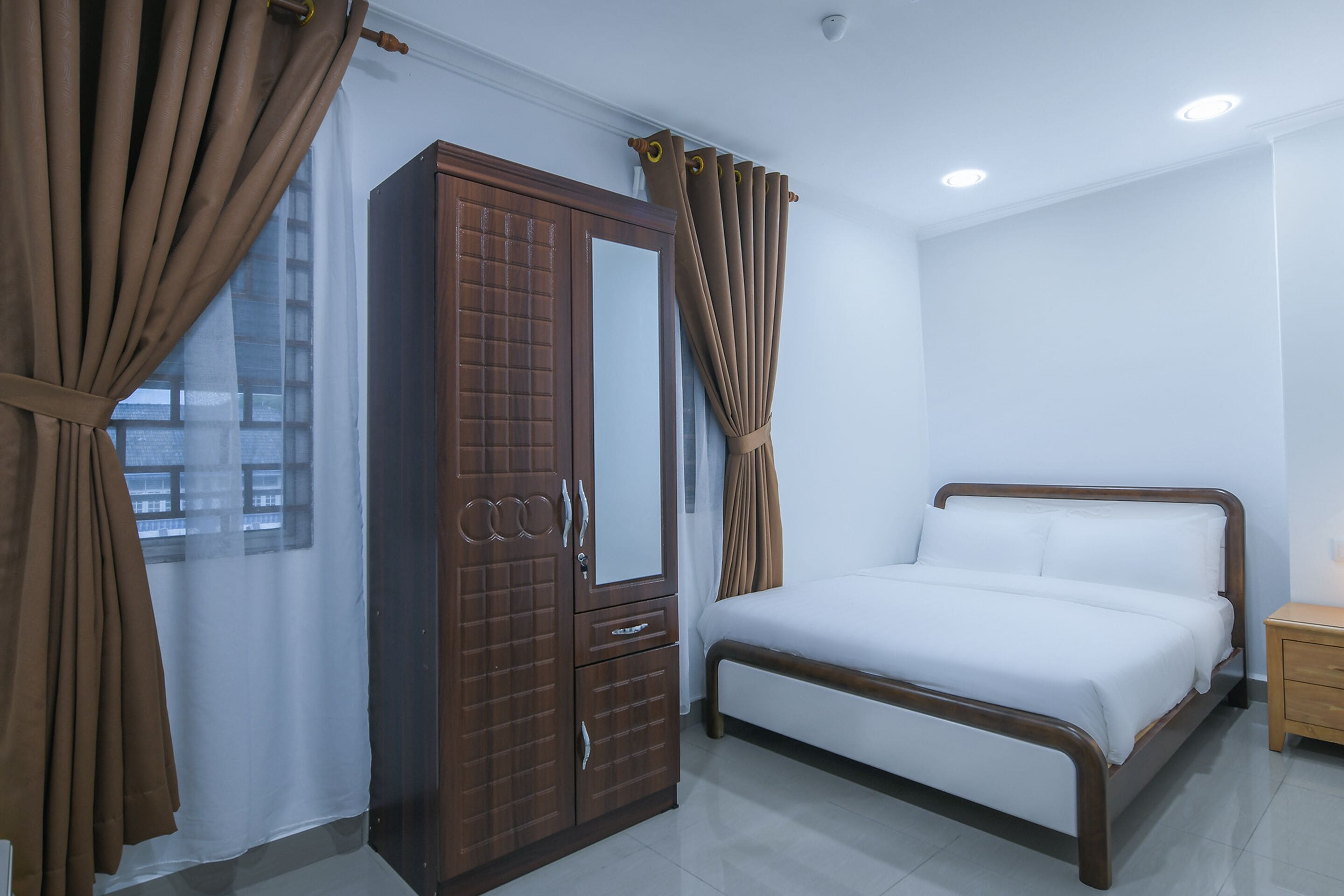Un dormitorio con cama, armario y cortinas.