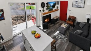 Ein modernes Wohnzimmer mit Kamin, Fernseher und einem Essbereich mit Obstschalen.