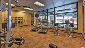 Un gimnasio con cintas de correr, elípticas y equipo de pesas.