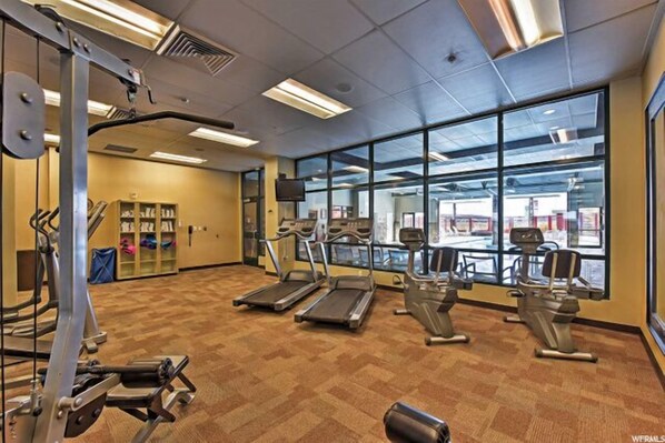 Une salle de sport équipée de tapis de course, de vélos elliptiques et de matériel de musculation.