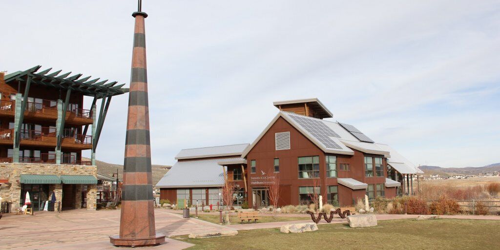 A modern building with a prominent tower, a sign reading "FARMER'S MARKET," and a stone facade.