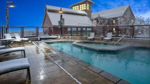 Un área de piscina con sillas de descanso y un edificio con tejado nevado.