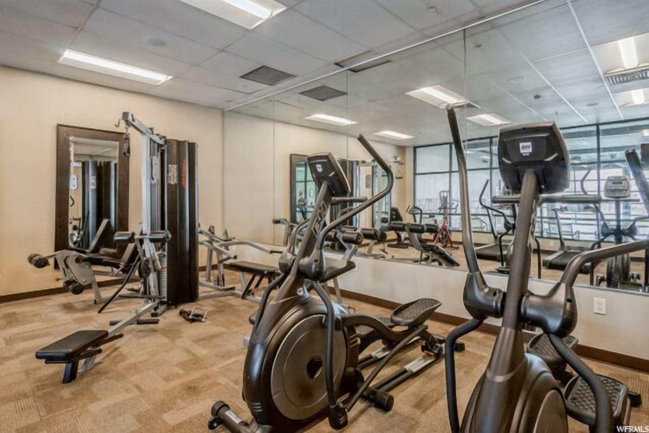 Une salle de sport équipée de matériel d’exercice, de miroirs et dotée d’un plancher en bois.