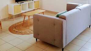 A living room with a sofa, TV, and a woven light fixture.