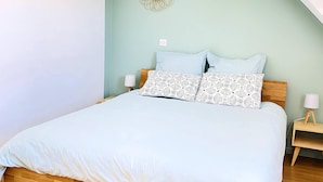 A bedroom with a wooden bed, light blue walls, and a decorative mirror on the wall.