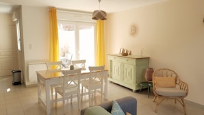 A dining area with a table and chairs, a green cabinet, and a wicker chair.