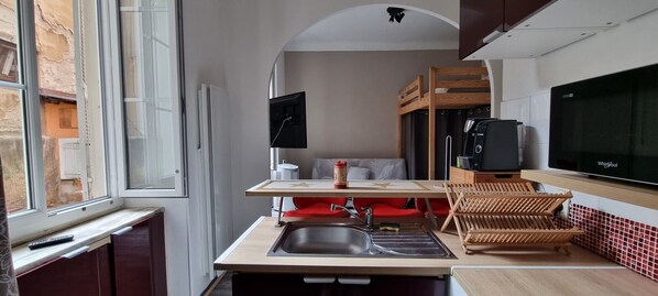 A compact kitchen with a sink, a microwave, a refrigerator, and a dining area with a table and chairs.