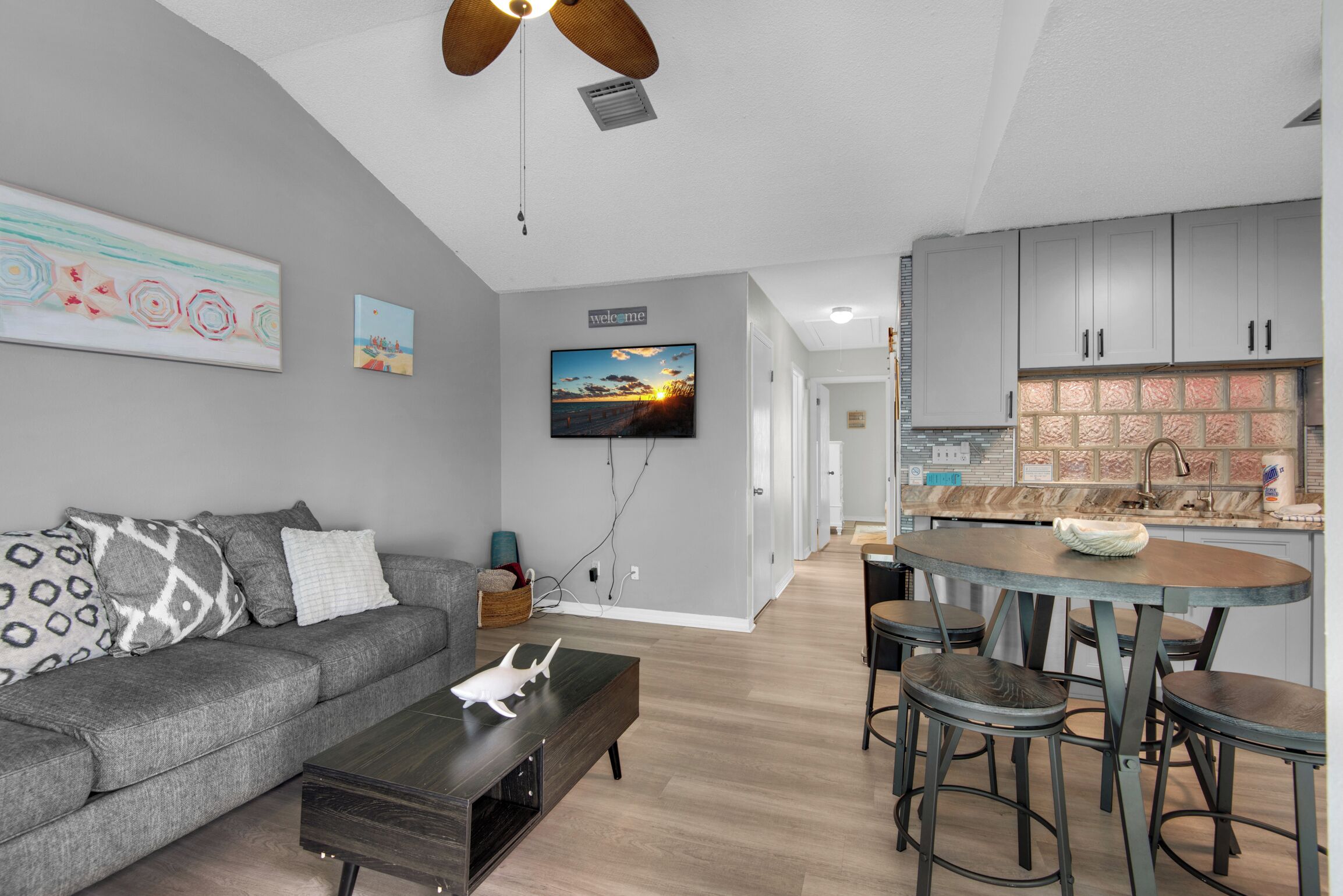 A modern living room with a grey sofa, a coffee table, and a TV mounted on the wall.