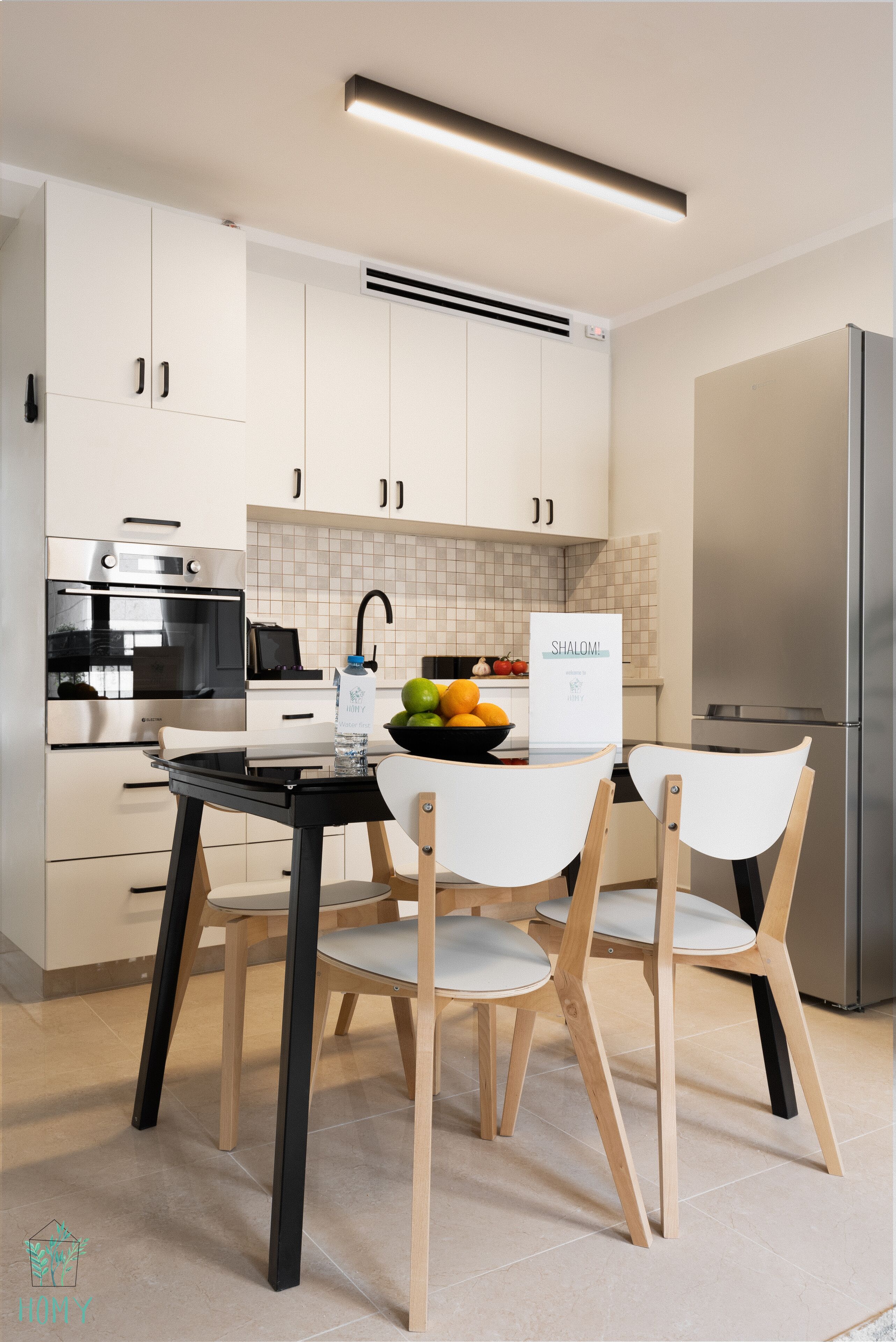 Una cocina moderna con armarios blancos, una encimera negra y un refrigerador de acero inoxidable.