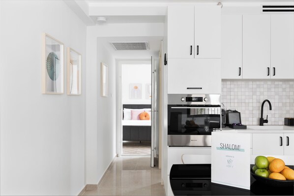A modern kitchen with white cabinets, a built-in oven, and a black countertop.