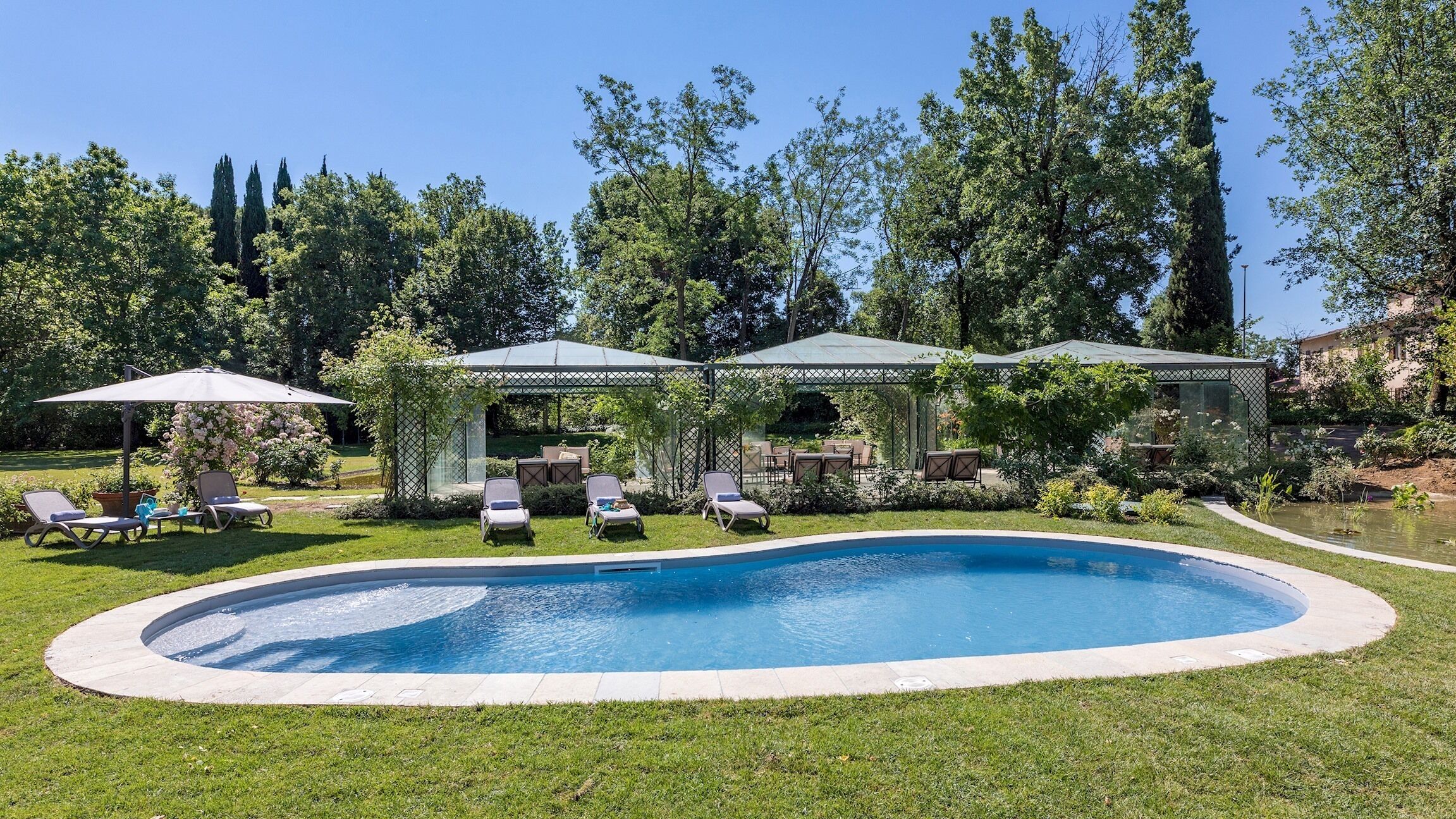 A swimming pool with lounge chairs and a covered patio area.