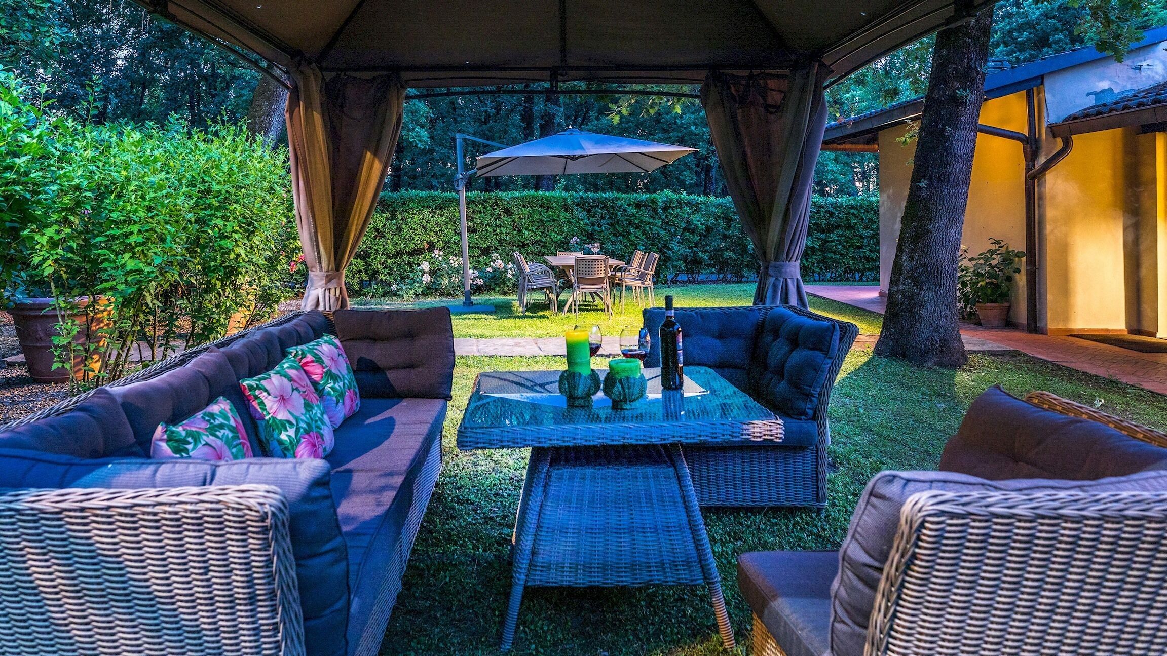 Una terrazza esterna con mobili in vimini, un tavolo con bevande e una zona salotto coperta.