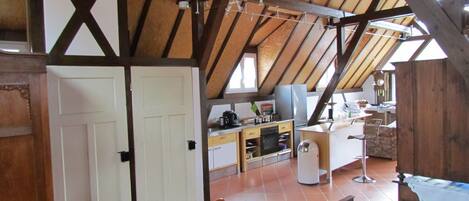 Une cuisine rustique avec des poutres en bois, une porte blanche et un coin repas comprenant une table et des chaises en bois.